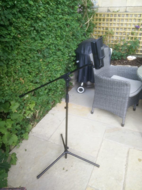 Image of boom microphone stand with the extended arm is positioned above one of the legs