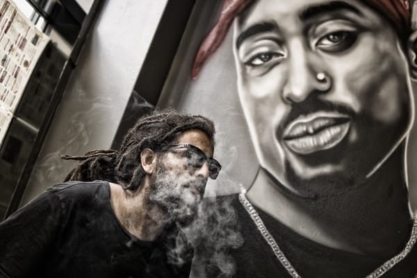 Tupac poster behind a rapper smoking